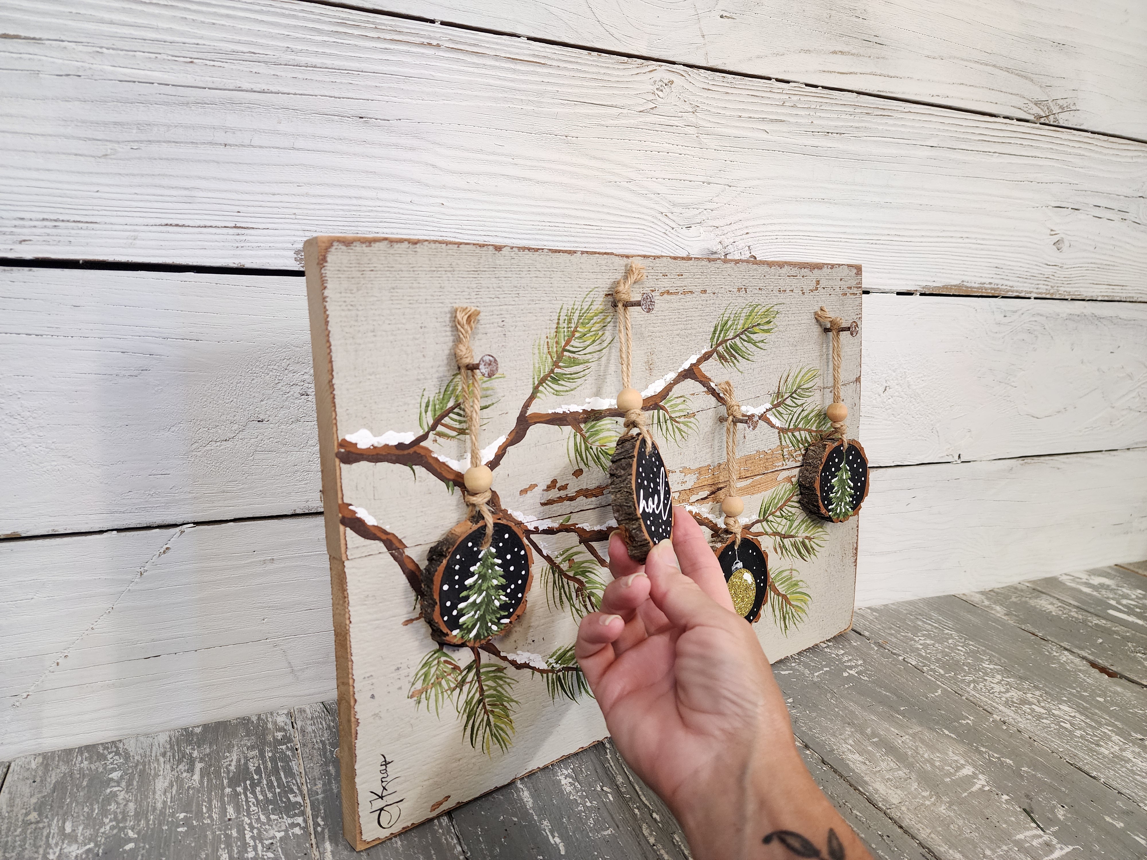 Noel Christmas handmade wood slice ornaments on snow covered pine tree branch, recycled holiday artwork, black and gold accents, tan antique